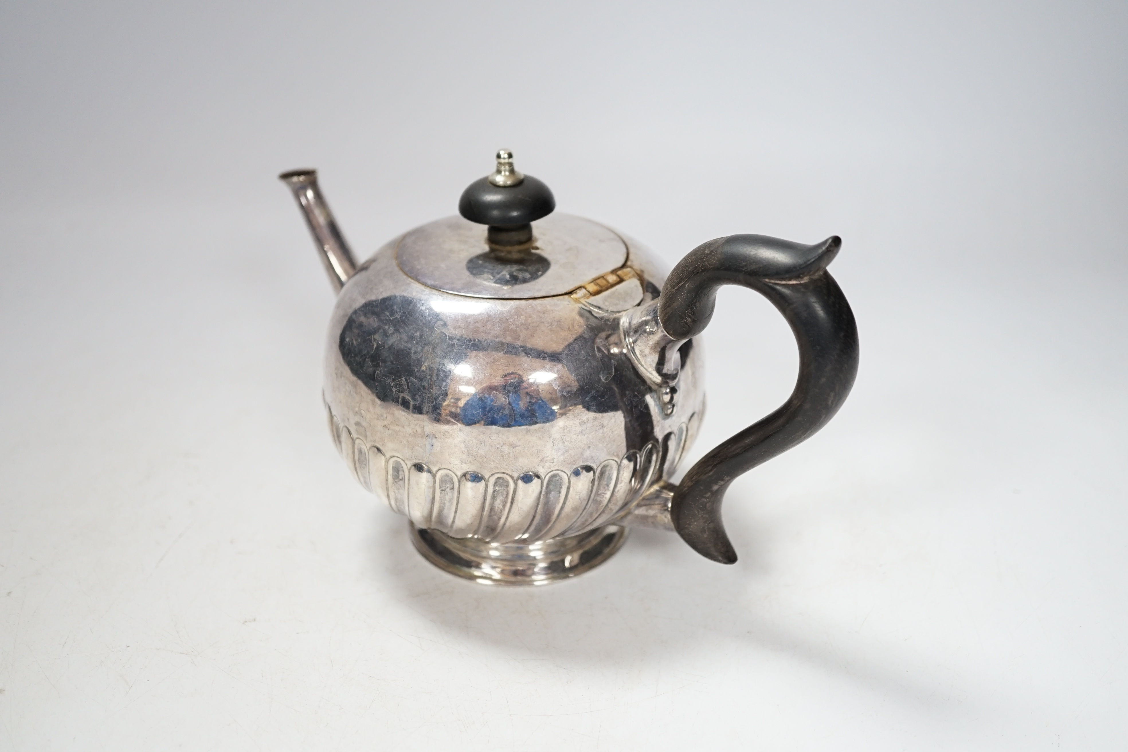 A Victorian silver bullet shaped teapot, with ebonised handle and gadrooned body, marks rubbed, London 1895, gross 321 grams